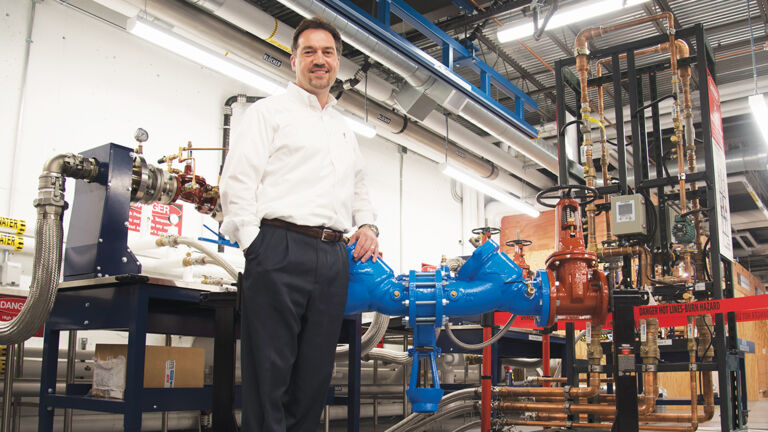 Man standing in front of a large blue backflow valve.